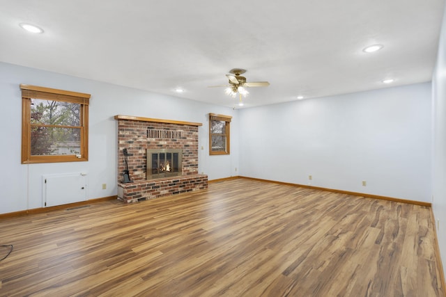 unfurnished living room featuring hardwood / wood-style floors, ceiling fan, and a fireplace