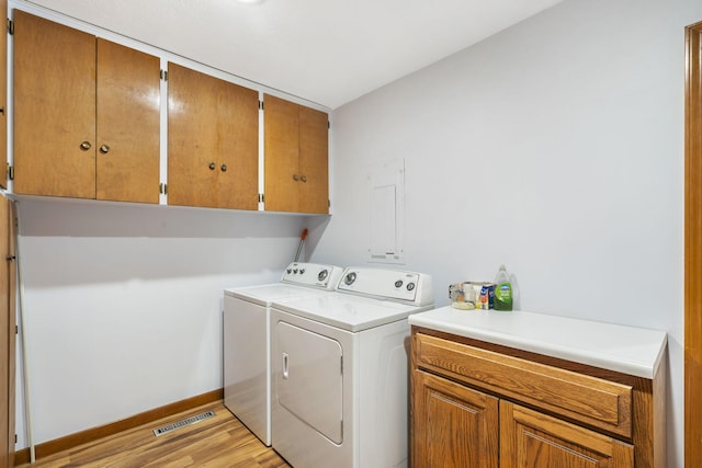 washroom with washer and dryer, cabinets, and light hardwood / wood-style flooring