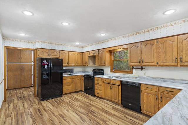 kitchen featuring sink, black appliances, and light wood-type flooring