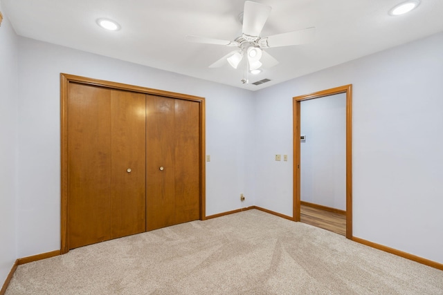 unfurnished bedroom featuring ceiling fan, a closet, and light carpet