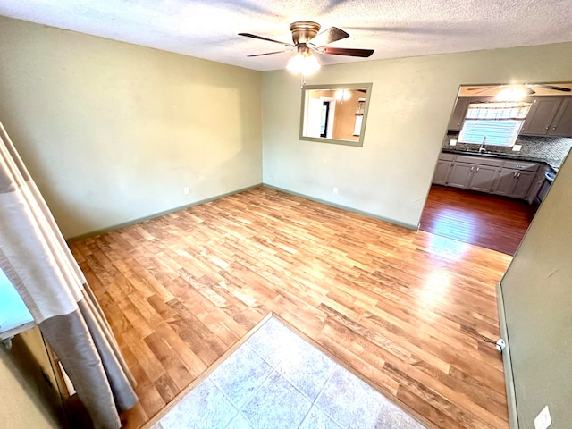 spare room with ceiling fan, sink, a textured ceiling, and light hardwood / wood-style flooring