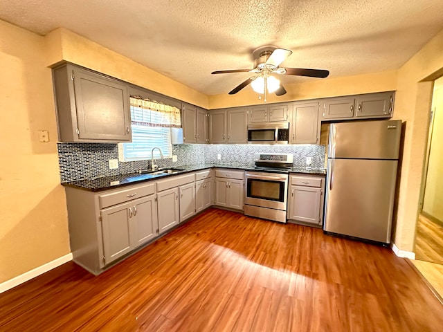 kitchen with gray cabinetry, a textured ceiling, stainless steel appliances, ceiling fan, and hardwood / wood-style flooring