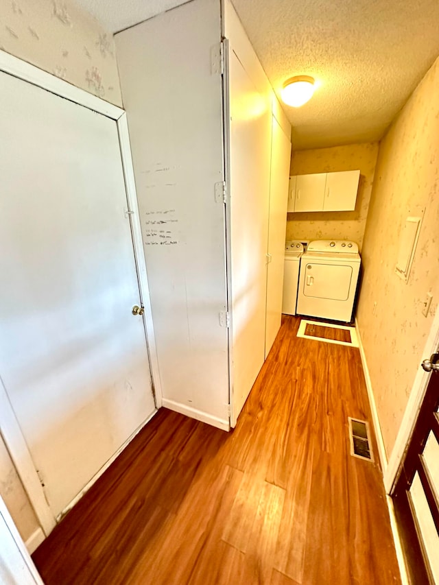 corridor with light hardwood / wood-style flooring, washer and dryer, and a textured ceiling