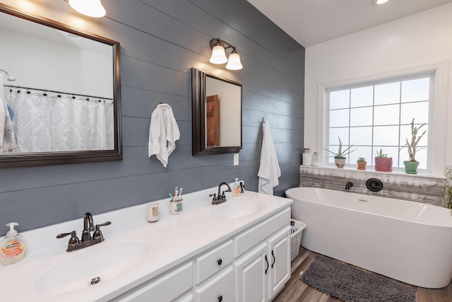 bathroom featuring a tub, wood walls, vanity, and hardwood / wood-style flooring