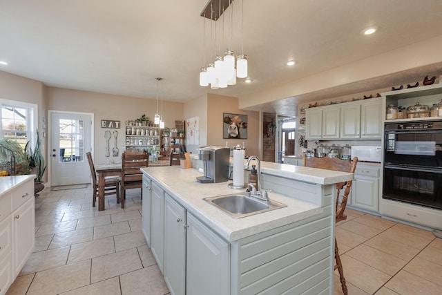 kitchen featuring pendant lighting, sink, a kitchen island with sink, and double oven