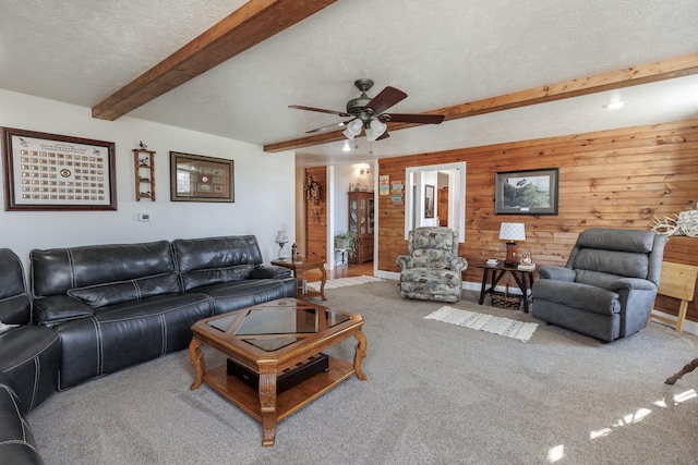 living room with carpet, wooden walls, beamed ceiling, and a textured ceiling