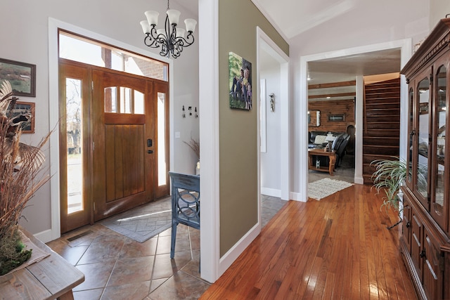 foyer featuring dark hardwood / wood-style flooring, an inviting chandelier, plenty of natural light, and lofted ceiling