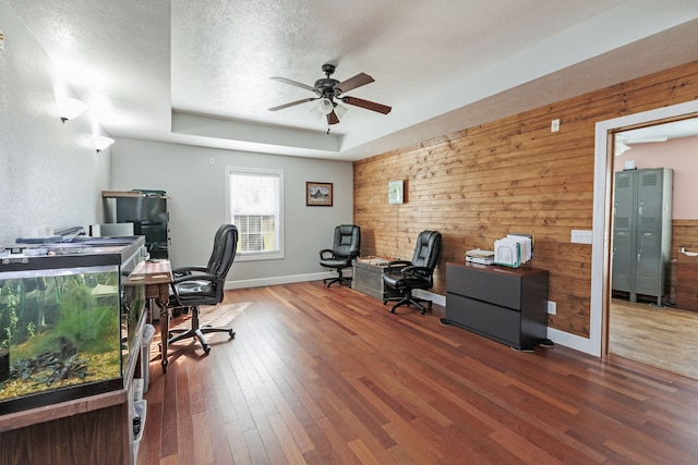 home office with dark hardwood / wood-style floors, ceiling fan, a textured ceiling, and wooden walls