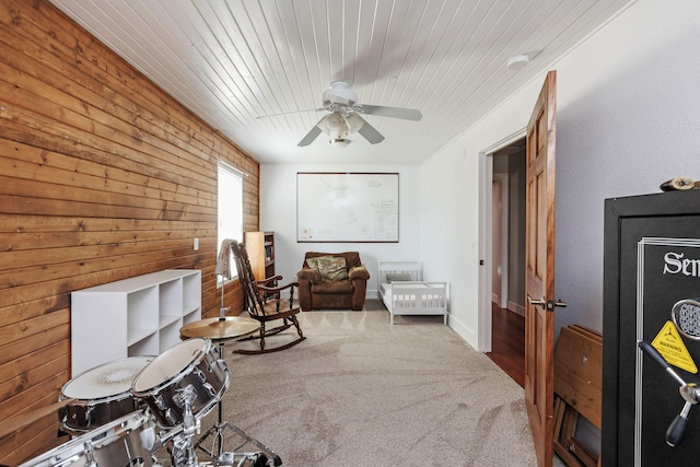 sitting room with carpet flooring, ceiling fan, wooden ceiling, and wood walls