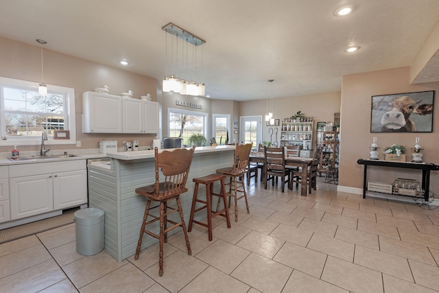 kitchen with sink, decorative light fixtures, white cabinets, a center island, and a breakfast bar area