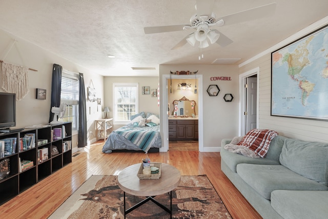 living room with a textured ceiling, light hardwood / wood-style flooring, and ceiling fan