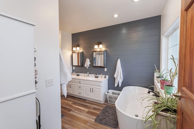 bathroom featuring wood walls, a washtub, vanity, and wood-type flooring