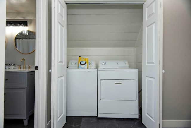 laundry area featuring separate washer and dryer, dark tile patterned flooring, and sink