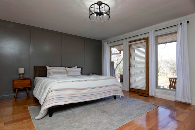 bedroom with light hardwood / wood-style floors, an inviting chandelier, and multiple windows