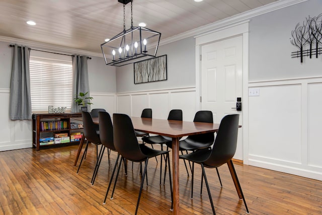 dining area with hardwood / wood-style floors, an inviting chandelier, and ornamental molding