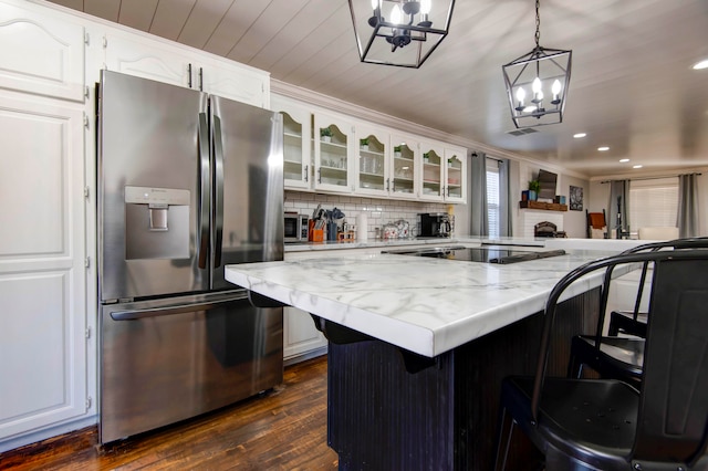 kitchen with dark wood-type flooring, white cabinets, stainless steel appliances, and decorative light fixtures