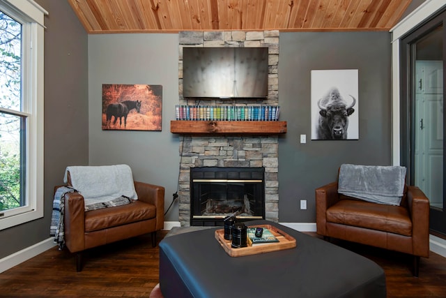 living room with dark hardwood / wood-style flooring, a stone fireplace, a wealth of natural light, and wood ceiling