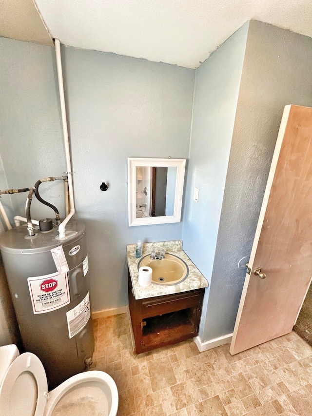 bathroom with baseboards, vanity, stone finish floor, and electric water heater