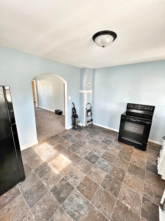 unfurnished room with arched walkways, stone finish floor, a textured ceiling, and baseboards