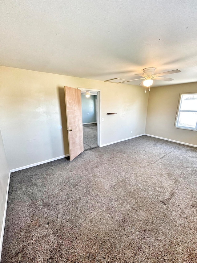 carpeted empty room with a ceiling fan, a textured ceiling, and baseboards