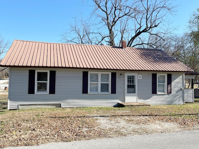 view of front of property featuring a chimney and metal roof