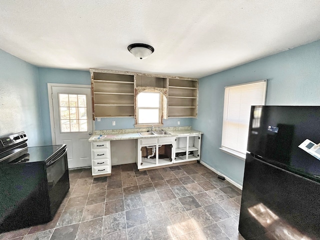 kitchen with a sink, light countertops, black appliances, open shelves, and a wealth of natural light