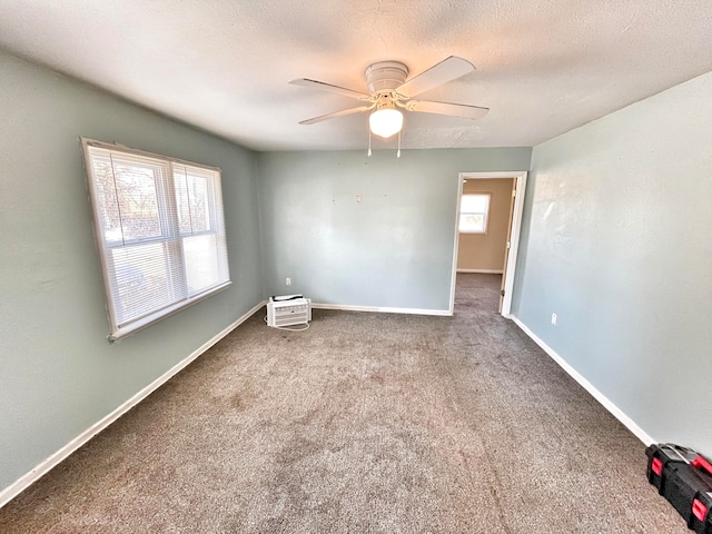 spare room with a ceiling fan, carpet, baseboards, and a textured ceiling