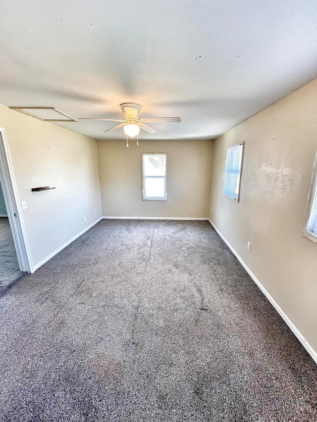 unfurnished room with a textured ceiling, carpet floors, a ceiling fan, and baseboards