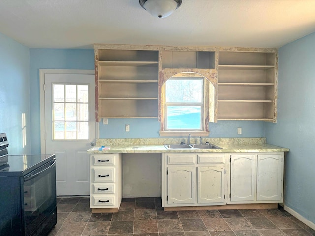 kitchen featuring open shelves, black / electric stove, light countertops, and a sink