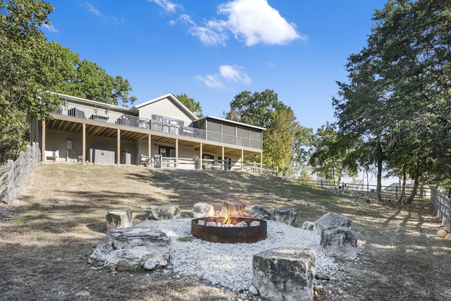 back of house with a sunroom, fence, and a fire pit