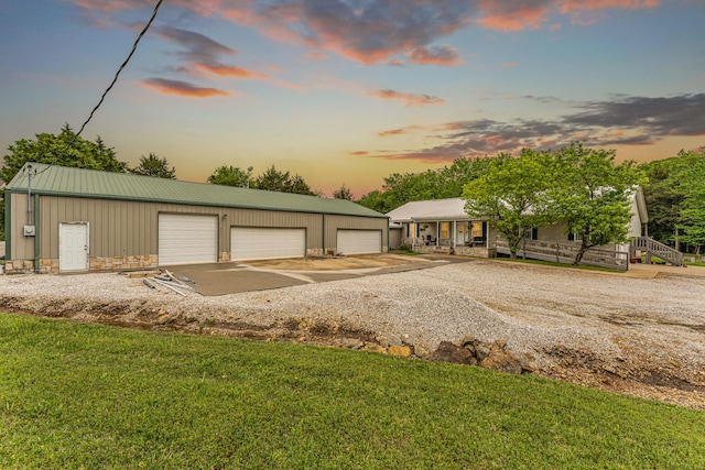 ranch-style house with a lawn, a garage, an outdoor structure, and covered porch