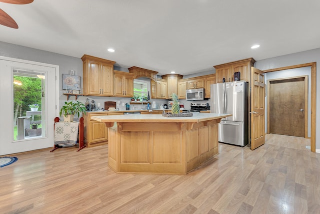 kitchen with a center island, a kitchen bar, light hardwood / wood-style floors, and stainless steel appliances