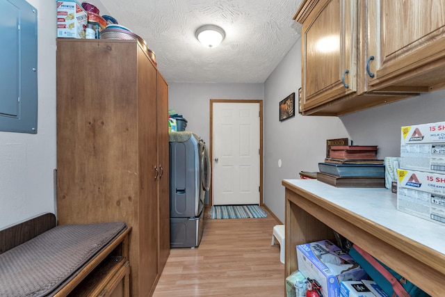 washroom with cabinets, electric panel, a textured ceiling, washer and dryer, and light wood-type flooring