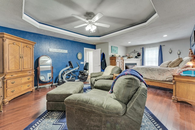 bedroom with a tray ceiling, ceiling fan, and dark wood-type flooring