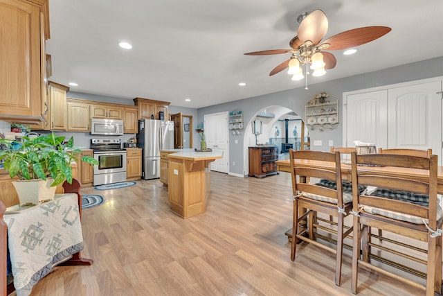 kitchen featuring light wood-type flooring, appliances with stainless steel finishes, a center island, and ceiling fan