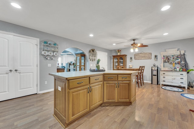 kitchen with light hardwood / wood-style floors, a kitchen island, and ceiling fan