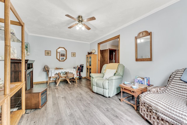 living room featuring a textured ceiling, ceiling fan, light wood-type flooring, and ornamental molding