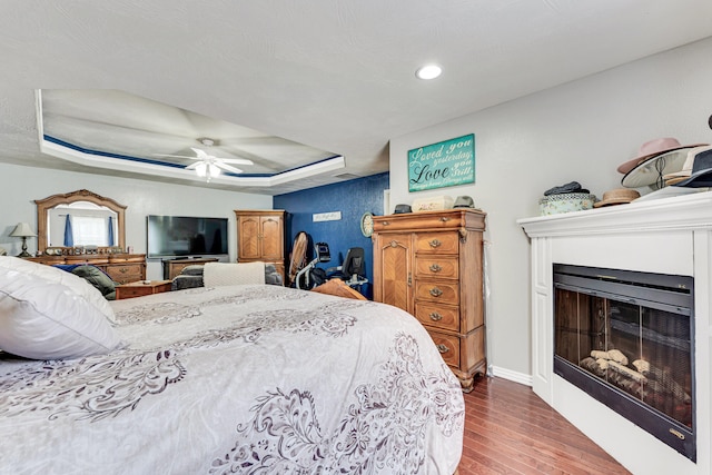 bedroom featuring a raised ceiling, ceiling fan, and dark hardwood / wood-style floors