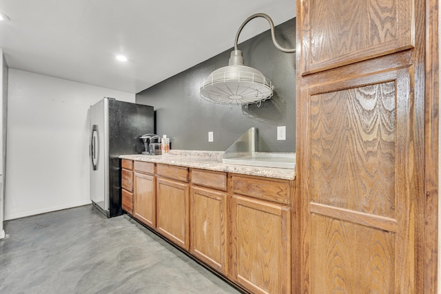 kitchen featuring light stone countertops, stainless steel fridge, and pendant lighting