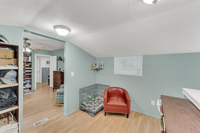 living area with a textured ceiling, ceiling fan, vaulted ceiling, and hardwood / wood-style flooring