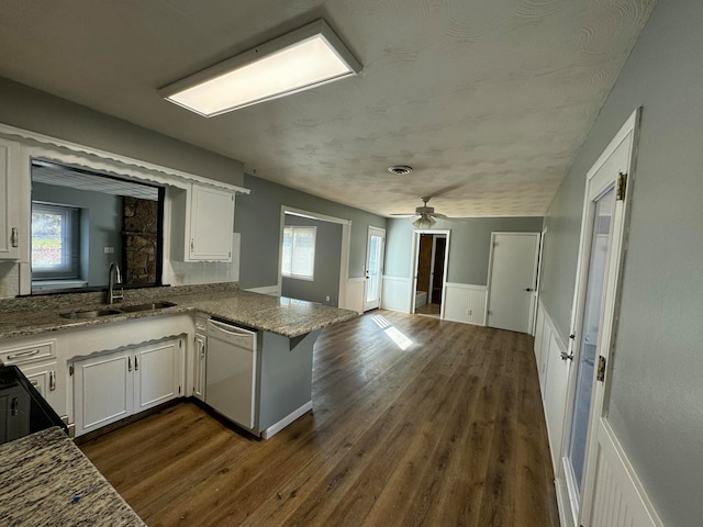 kitchen featuring dishwasher, sink, dark wood-type flooring, kitchen peninsula, and white cabinets