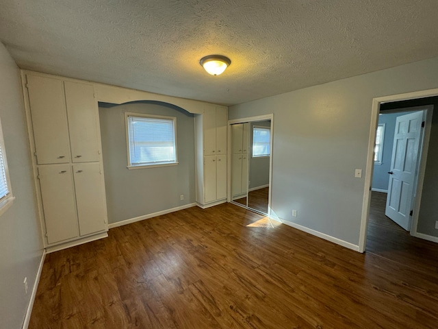 unfurnished bedroom with dark wood-type flooring and a textured ceiling