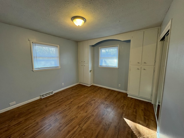 unfurnished bedroom with dark hardwood / wood-style flooring and a textured ceiling