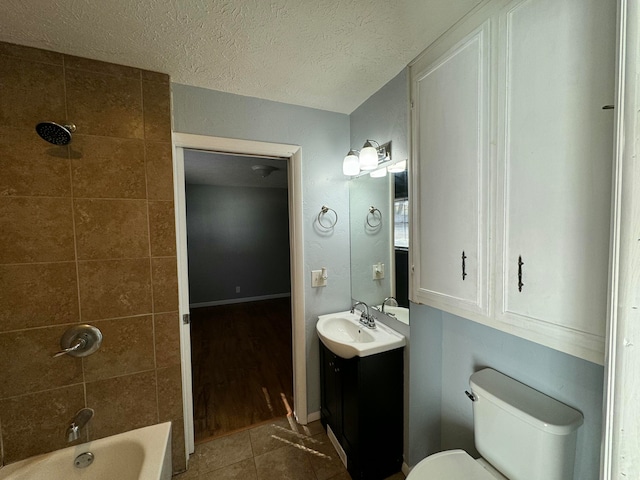 full bathroom with vanity, a textured ceiling, tile patterned flooring, toilet, and tiled shower / bath