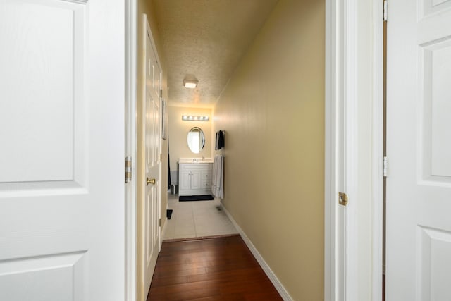 corridor featuring a textured ceiling and hardwood / wood-style flooring