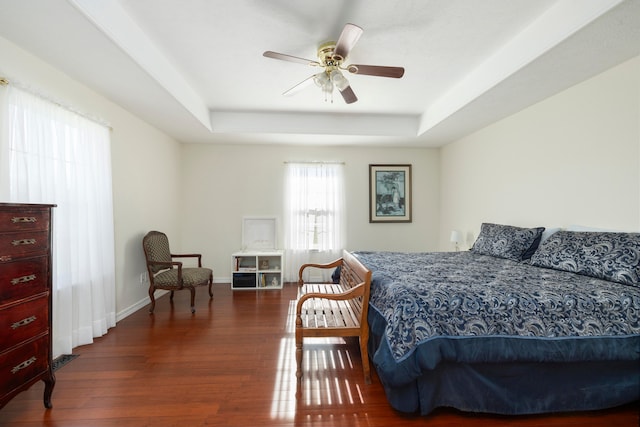 bedroom featuring dark hardwood / wood-style floors, ceiling fan, and a raised ceiling