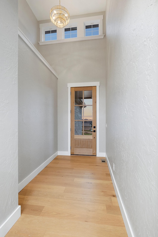 corridor featuring hardwood / wood-style flooring and an inviting chandelier