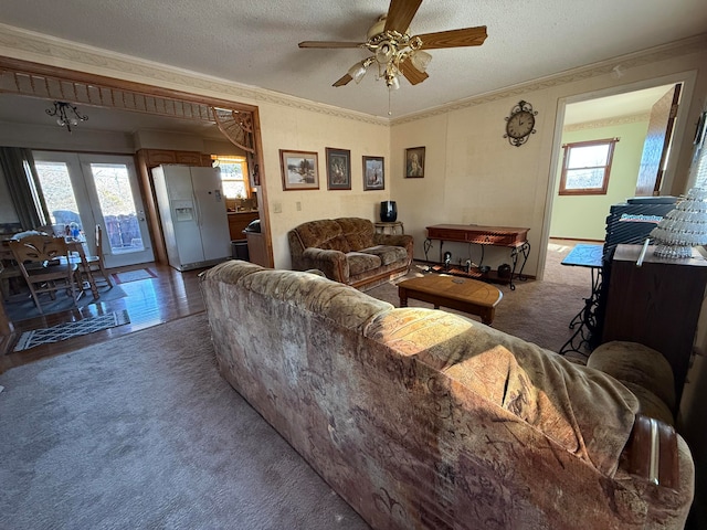 living room with crown molding, ceiling fan, dark carpet, and a textured ceiling