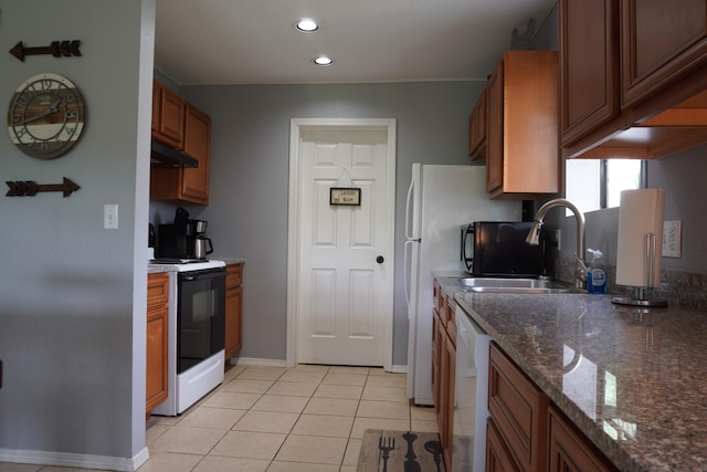 kitchen featuring light tile patterned floors, white appliances, dark stone counters, and sink