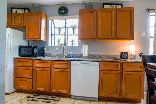 kitchen featuring sink, white dishwasher, stone countertops, and light tile patterned floors